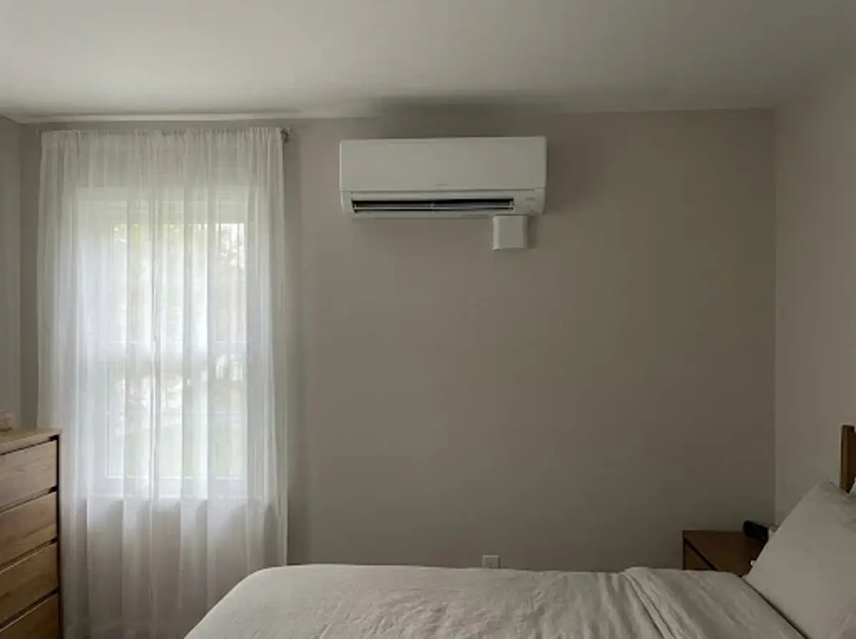 A white ductless mini-split unit mounted on a bedroom wall